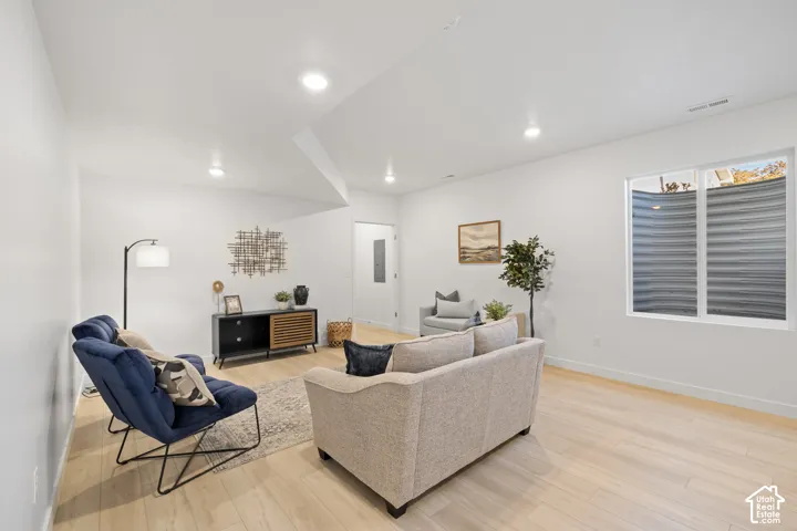 Spacious ADU living area featuring light wood-finish flooring, recessed lighting, and a window with blinds