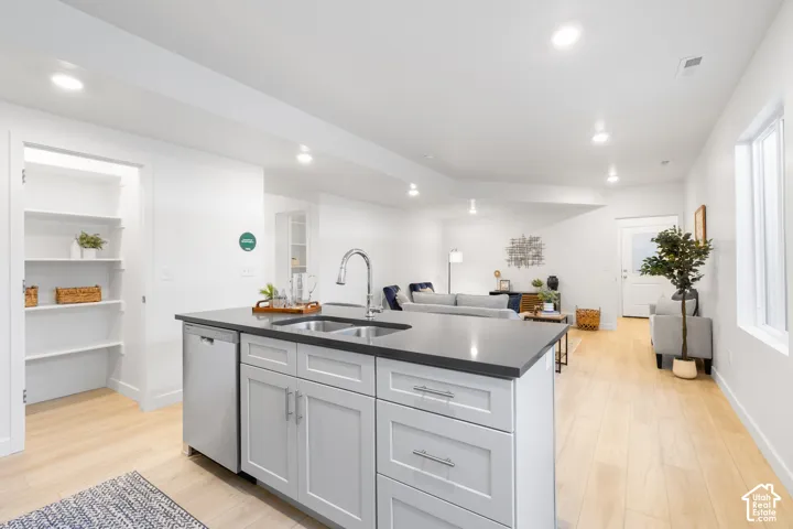 Kitchen island featuring a double-basin stainless steel sink, pull-down faucet, and integrated dishwasher