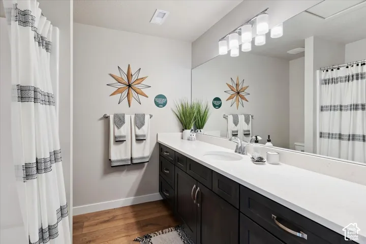 Bathroom featuring a spacious dark wood-finish vanity with dual sinks, white countertop, and an expansive wall-mounted mirror