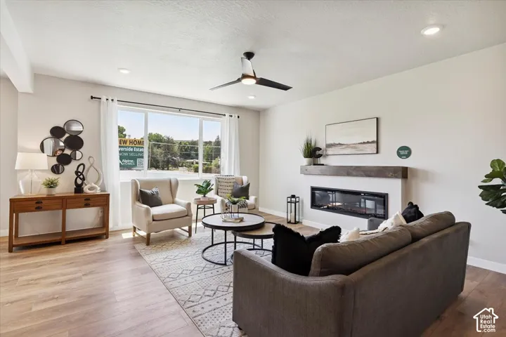 Spacious living area featuring wood-finish flooring, a contemporary linear fireplace with a wood mantel, and recessed lighting