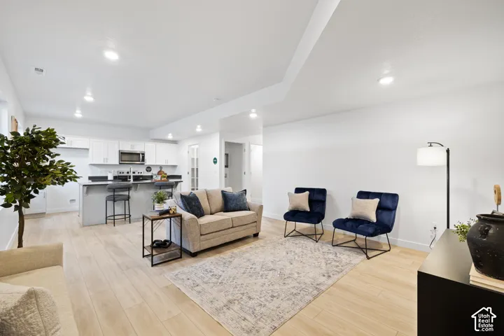 Open-concept ADU living area featuring light wood-finish flooring, recessed lighting, and white walls