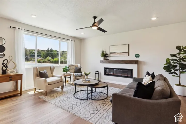 Spacious living area featuring large windows, wood-finish flooring, recessed lighting, and a ceiling fan