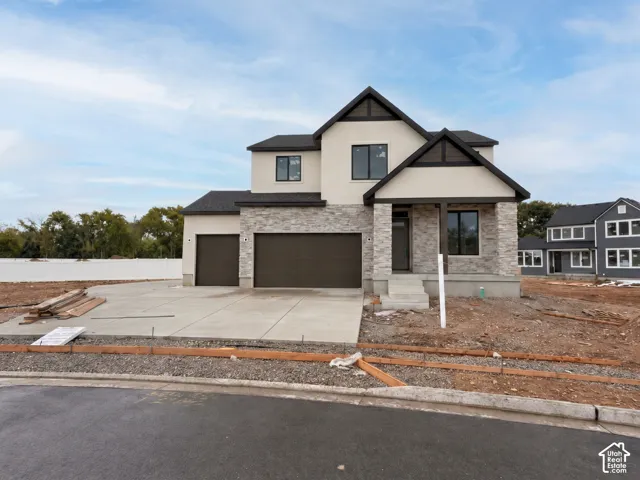 Two-story exterior featuring a stone veneer facade, stucco siding, a three-car garage, and a covered front porch entry