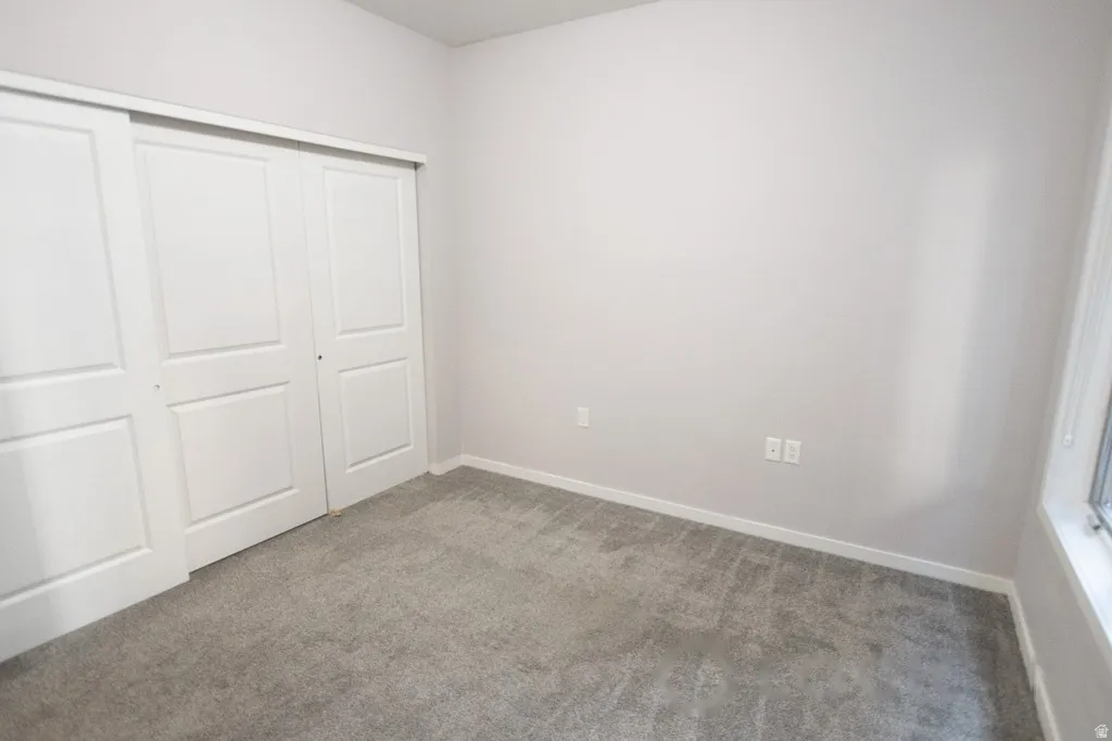 Room with light gray walls, gray carpet flooring, and white trim