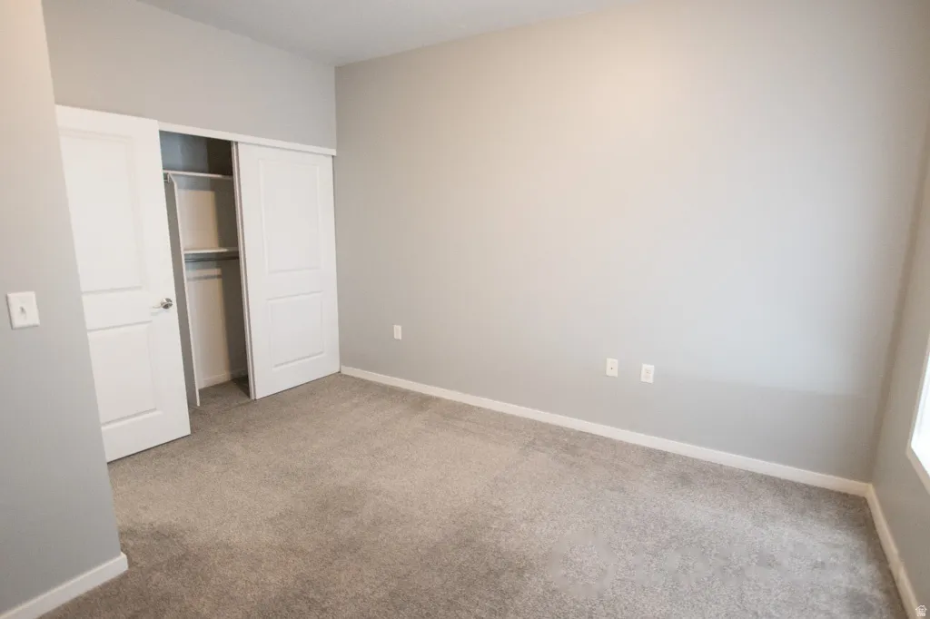 Carpeted room featuring a white trim baseboard, light gray walls, and a recessed ceiling light