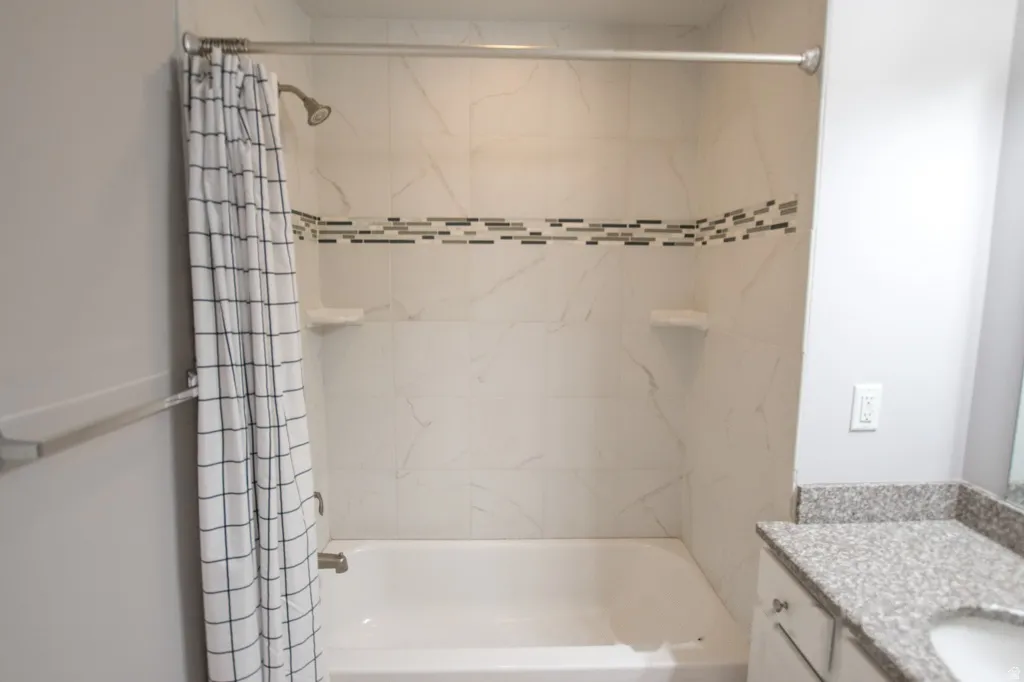 Tiled shower and bathtub combination featuring a decorative mosaic accent band