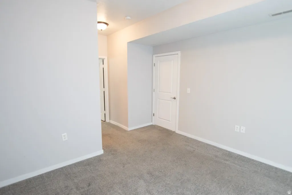 Spacious room featuring neutral grey carpeting and light grey wall paint