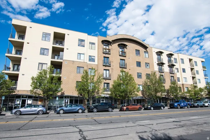 Multi-story building featuring a mixed-material facade with tan stucco and light brown brickwork