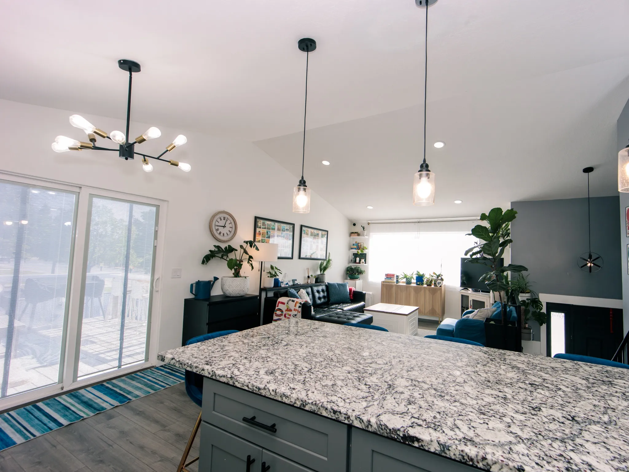 Kitchen island with a granite-style countertop and gray cabinetry, featuring modern pendant lighting