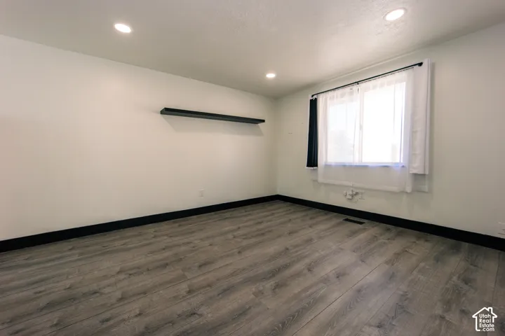 Room featuring wood-finish flooring, recessed lighting, and a wall-mounted floating shelf