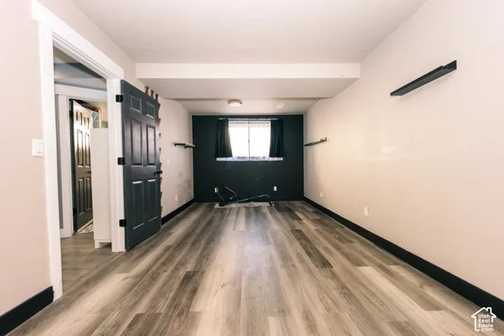 Interior room featuring wood-finish flooring, a dark-toned accent wall, and mounted shelving units