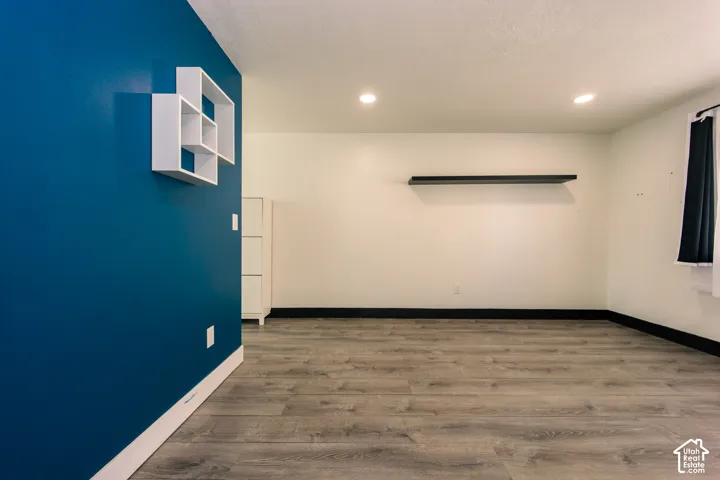 Wood-finish flooring, accent wall, built-in wall shelving, and recessed ceiling lighting