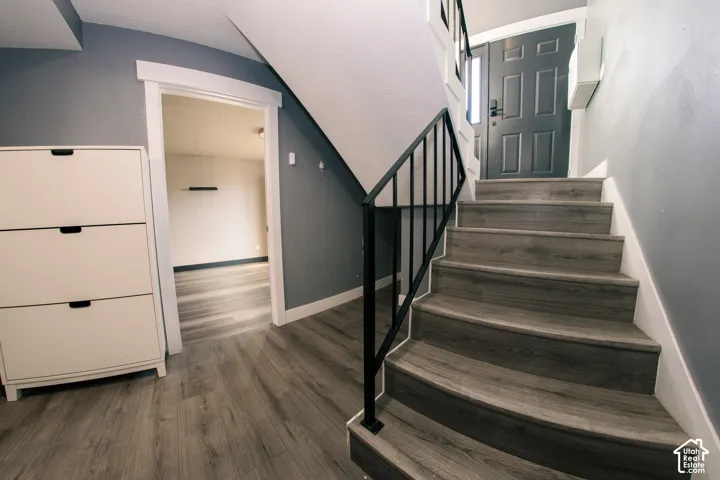 Entryway featuring wood-finish flooring, a matte black metal stair railing, and a multi-panel exterior door