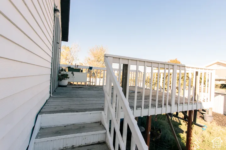 Raised wooden deck featuring a white railing and exterior wall-mounted light fixture