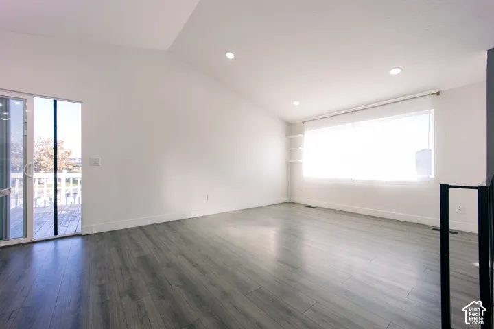 Vaulted ceilings, wood-finish flooring, recessed lighting, expansive picture window, and sliding glass door
