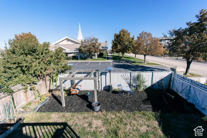 Enclosed backyard featuring a structural timber pergola, mulched landscaping, and a perimeter wooden privacy fence