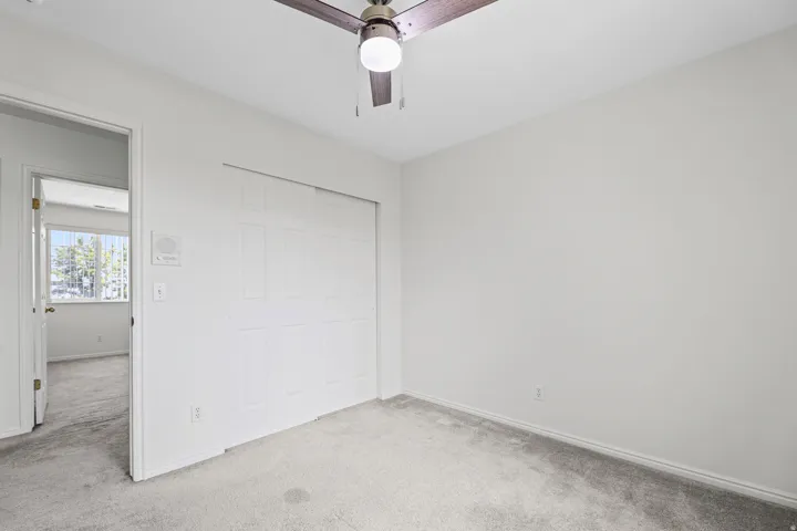 Carpeted room featuring a ceiling fan with integrated lighting, a bifold closet, and a white interior door