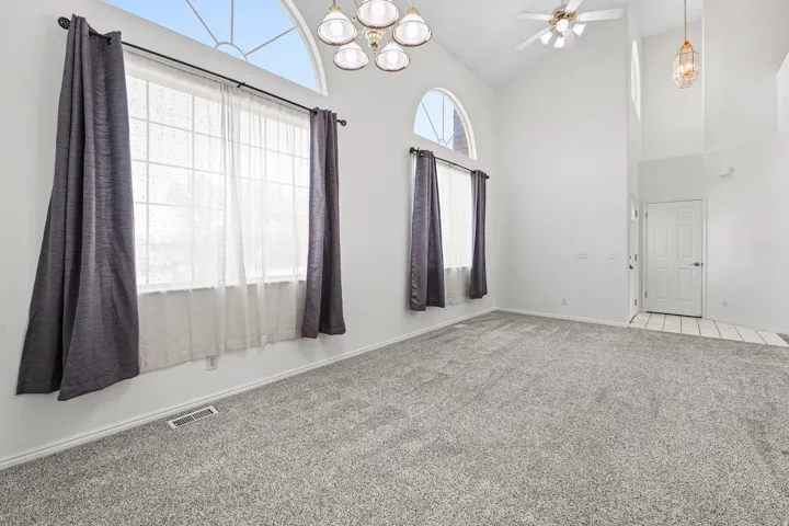 Vaulted ceilings with a ceiling fan, arched transom windows, and a multi-light chandelier
