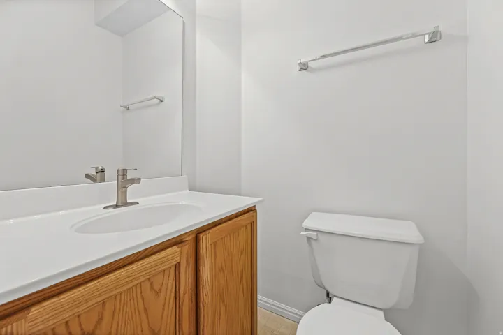 Bathroom featuring a wood-finish vanity with a white countertop, an integrated sink, a brushed nickel faucet, and a large wall mirror