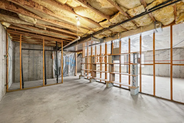 Expansive unfinished basement featuring a concrete floor, concrete foundation walls, exposed wood framing, and ceiling insulation
