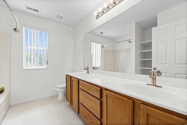 Bathroom featuring a double vanity with wood cabinetry, brushed nickel faucets, and a large mirror
