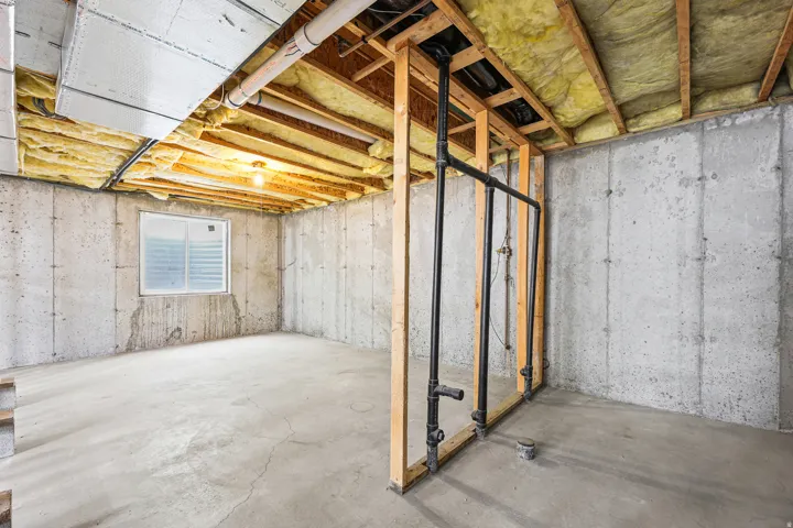 Unfinished basement featuring exposed joists with insulation, concrete walls, and concrete flooring