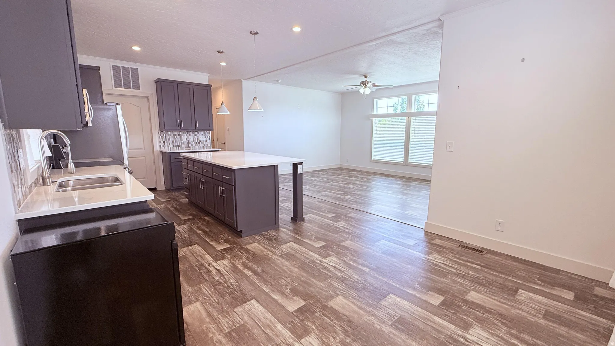 Open-concept kitchen featuring wood-finish flooring, recessed lighting, and a kitchen island with pendant lighting