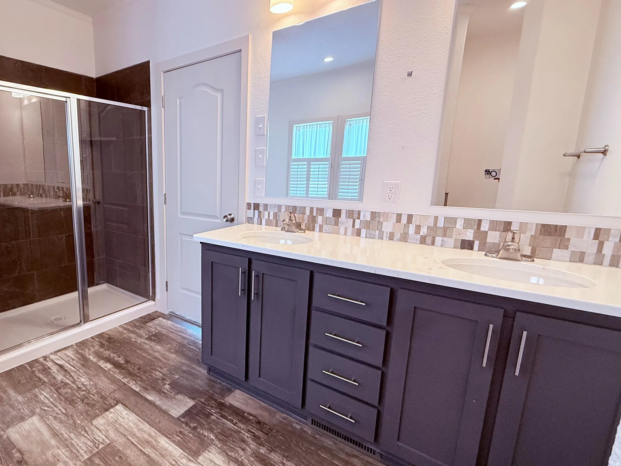 Dual vanity with white countertops, undermount sinks, and stand alone walk-in shower in Primary Bathroom