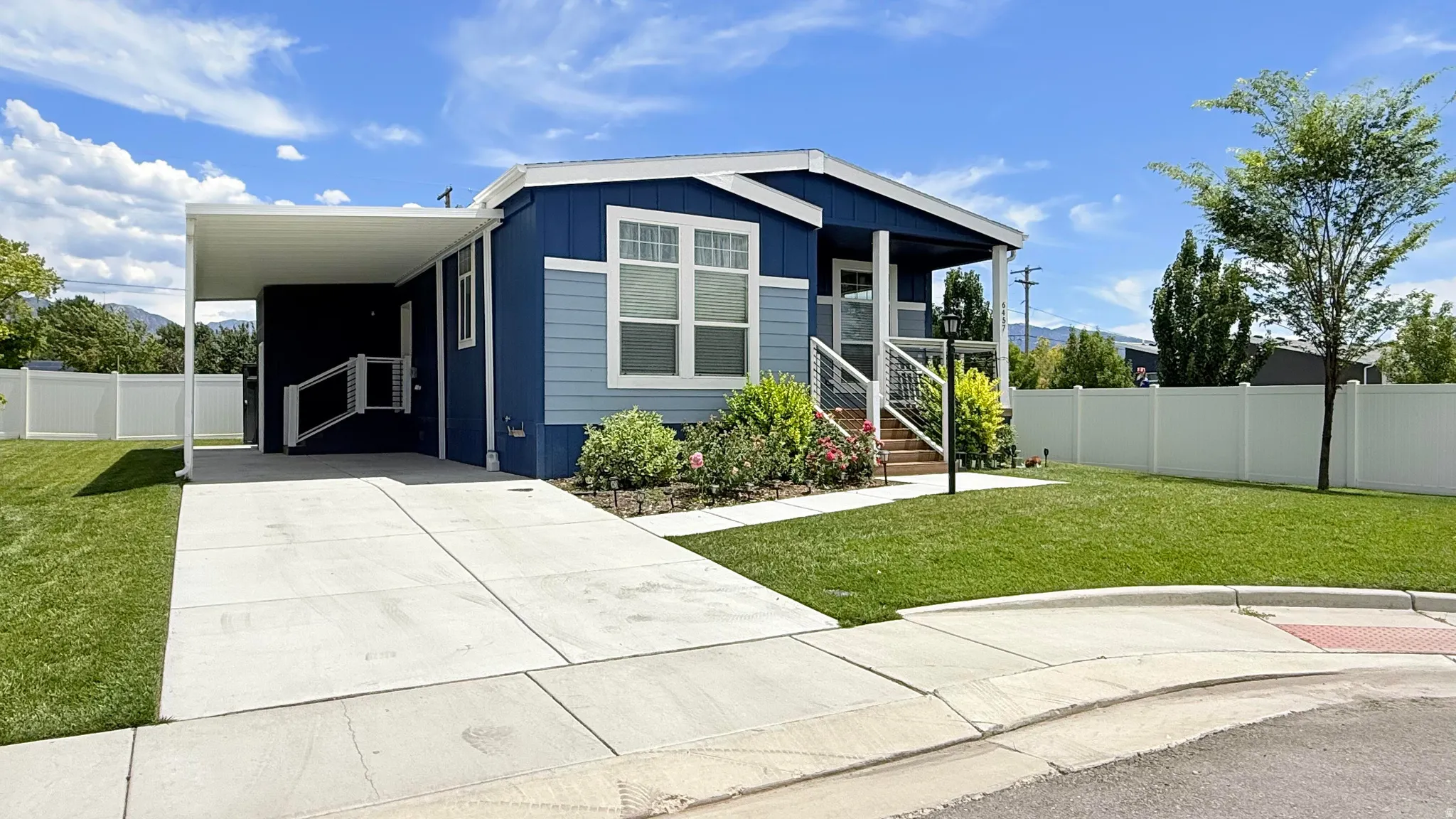 Contemporary home with blue siding, a covered carport, and a concrete driveway