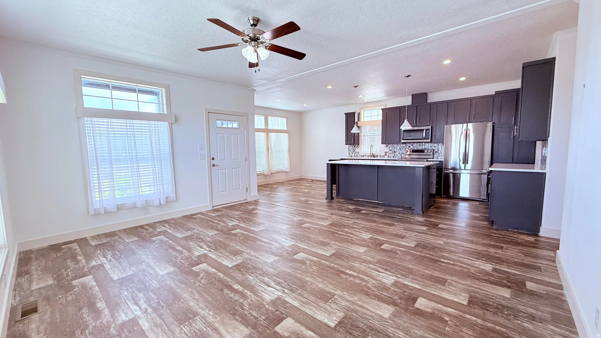 Open-concept living space, a ceiling fan with integrated lighting, and white trim
