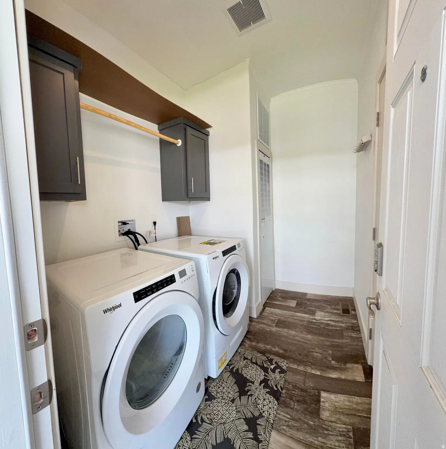 Dedicated laundry space featuring built-in wall cabinetry, and a clothes hanging rod