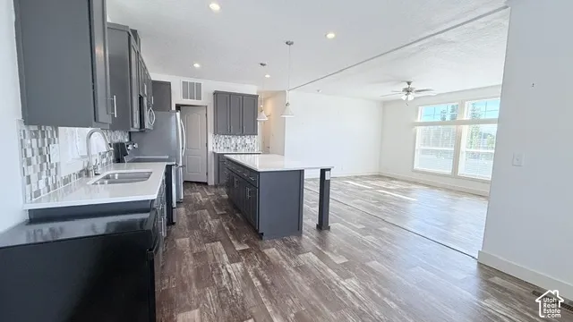 Kitchen featuring dark grey cabinetry, white countertops, tile backsplash, and wood-finish flooring