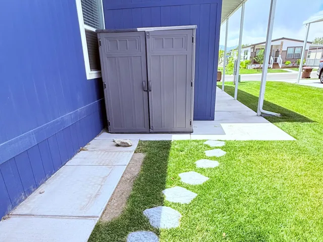 Included shed, vibrant blue exterior siding with white trim, featuring a side walkway with stepping stones and a covered patio area