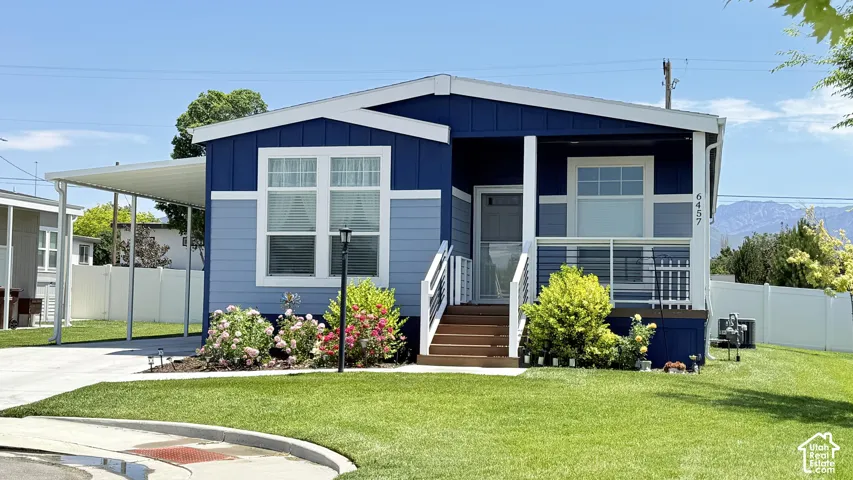 Contemporary home with a blue and light blue exterior, featuring a white trim and a covered carport