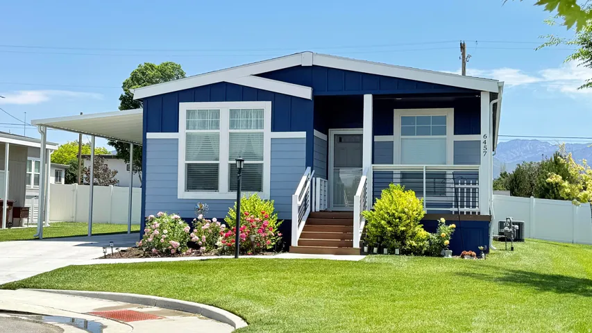 Contemporary home with a blue and light blue exterior, featuring a white trim and a covered carport