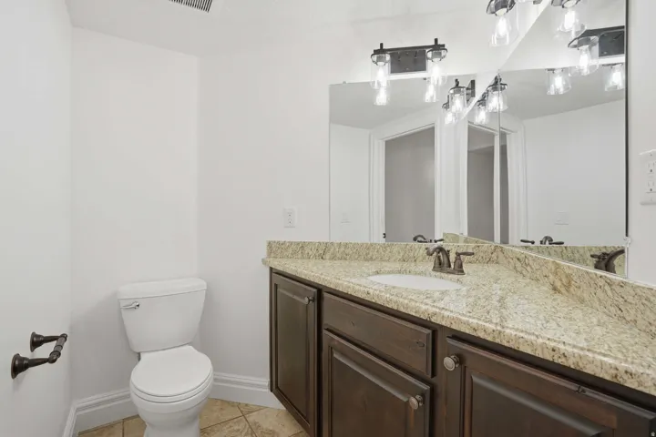 Bathroom featuring a granite countertop vanity with a white undermount sink, dark wood cabinetry, and oil-rubbed bronze fixtures
