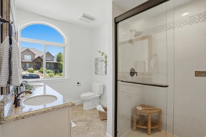 Bathroom featuring a glass-enclosed shower with tile surround, a built-in shower niche, and a vanity with an undermount sink and granite-style countertop