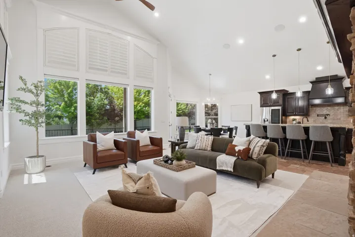 Spacious open-concept living area featuring vaulted ceilings, a prominent stone accent wall, and recessed lighting