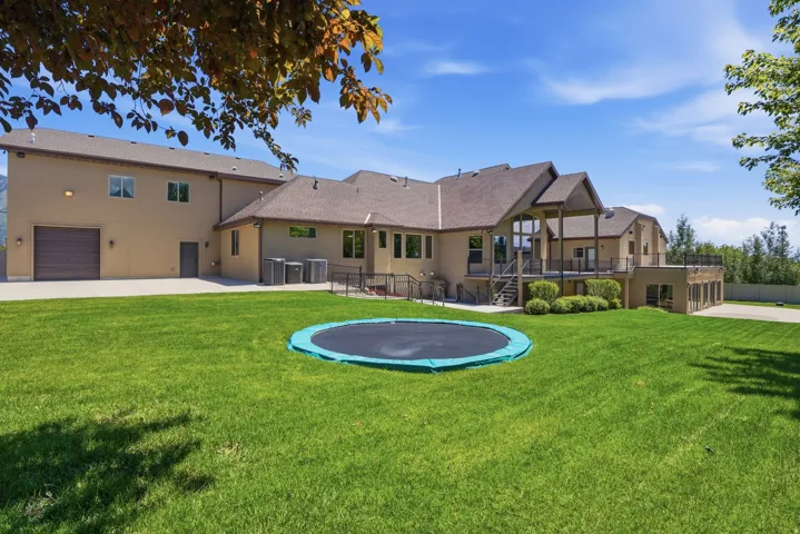 Expansive rear exterior featuring a substantial grass lawn, a multi-level deck, and a lower-level patio