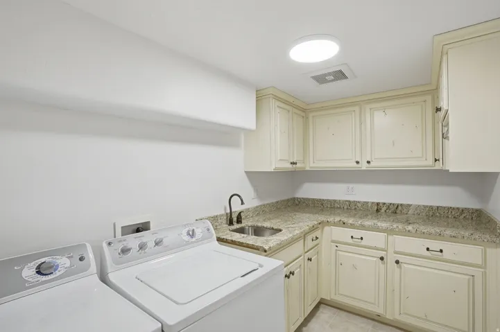 Utility room featuring an integrated sink, granite-style countertops, cream-finished cabinetry, and overhead lighting