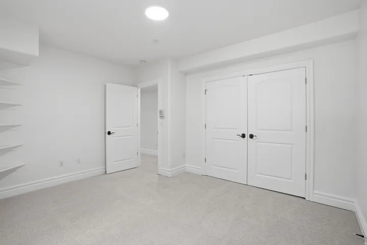 Light gray carpeted room featuring white walls, white trim, and a recessed ceiling light