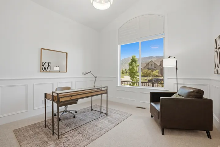 Bright room featuring a soaring vaulted ceiling, large picture window with an arched transom, and white wainscoting
