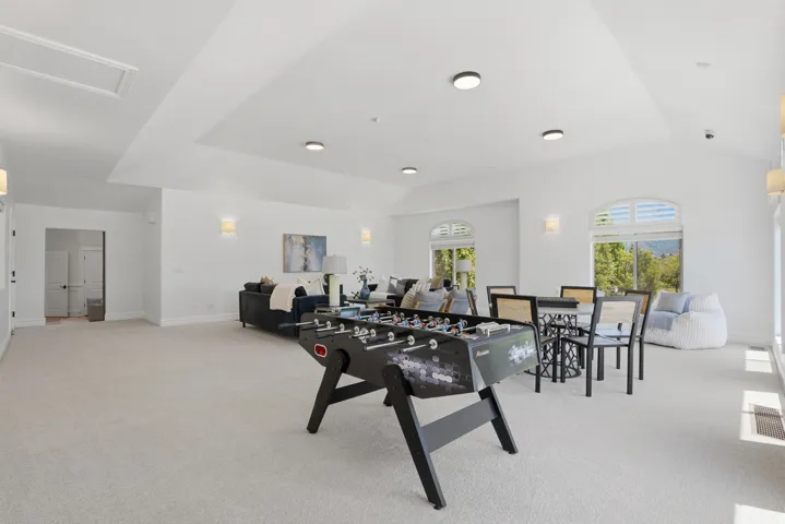 Spacious bonus room featuring vaulted ceilings, recessed lighting, and arched windows with plantation shutters