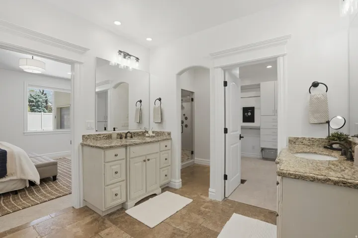 Bathroom featuring two separate vanities with stone countertops, a full-height mirror, and recessed lighting