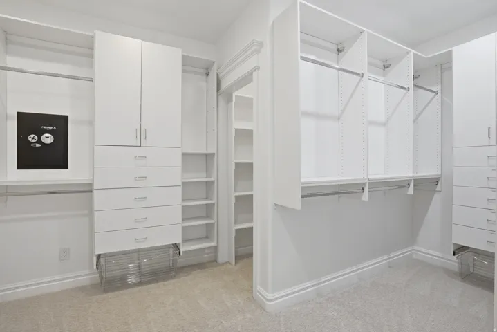 Custom closet organization system featuring white cabinetry and shelving