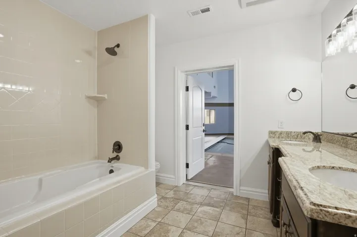 Bathroom featuring a white bathtub with a tiled surround and dark bronze fixtures