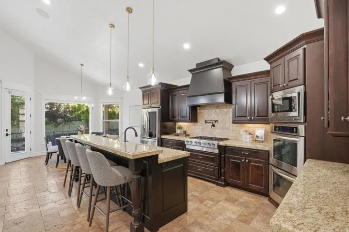 Kitchen featuring dark wood cabinetry, light-toned granite countertops, and stainless steel appliances