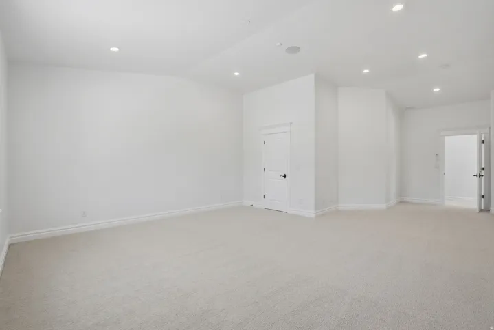 Spacious room featuring neutral carpeting, recessed ceiling lighting, and white baseboards