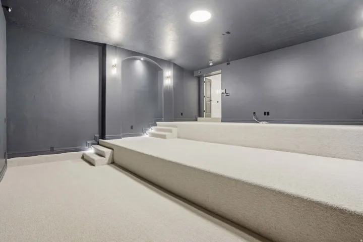 Tiered carpeted flooring with recessed step lighting, dark gray walls, and recessed ceiling lights