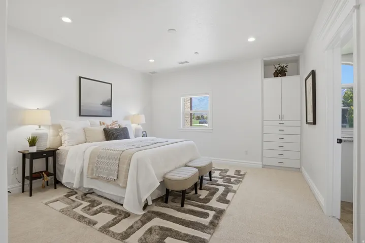 Bright bedroom featuring plush carpet flooring, recessed lighting, and a built-in wardrobe with both drawers and cabinet storage